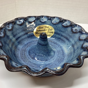 May include: Blue and white ceramic pie dish with a fluted edge and a center cone. The dish is labeled "Lead Free Dishwasher Safe Microwave Proof".