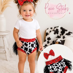 May include: A baby wearing a white onesie, cow print diaper cover with black fringe, and a red bandana bow headband. The diaper cover has a red paisley waistband and a black and white cow pattern. The bow headband matches the waistband.