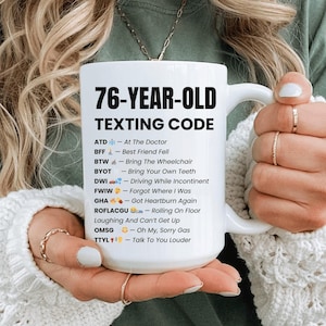 May include: White ceramic mug with the text "76-YEAR-OLD TEXTING CODE" in black. The mug lists common texting abbreviations with humorous definitions, such as "BFF - Best Friend Fell" and "DWI - Driving While Incontinent".