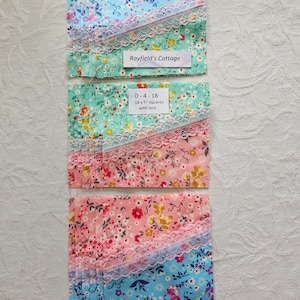 May include: A stack of 18, 5-inch fabric squares with lace trim in pink, blue, and green floral patterns. The fabric squares are labelled "Rayfield's Cottage" and "D-4-18 18 x 5" squares with lace".