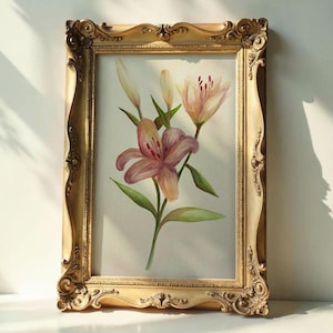 Pode incluir: Uma pintura em aquarela emoldurada de lírios rosa e amarelos com folhas verdes. A pintura está em uma moldura dourada ornamentada com um design vintage detalhado. A obra de arte é exibida em uma superfície branca.