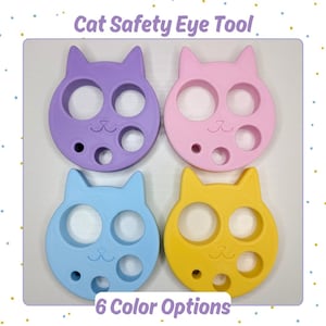 May include: Four cat-shaped safety eye tools in purple, pink, light blue, and yellow. Each tool features two large circular openings, two smaller circular openings, and a cat face engraving. The text Cat Safety Eye Tool and 6 Color Options is visible.