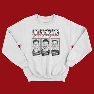 Könnte beinhalten: Weißes Sweatshirt mit dem Text "Nova Scotia Mafia" über drei Porträts im Fahndungsfoto-Stil. Jedes Porträt hat einen Namen darunter: "The Dogy", "The Kid" und "The Art". Das Sweatshirt hat lange Ärmel.