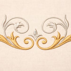 May include: Embroidered design featuring gold and silver floral elements on a cream-colored fabric. The symmetrical pattern includes stylized leaves, swirls, and a central fleur-de-lis, creating an elegant, decorative border.