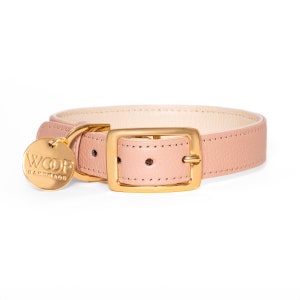 May include: A light pink leather dog collar with a gold buckle and a gold tag that says "WOOF HANDMADE".