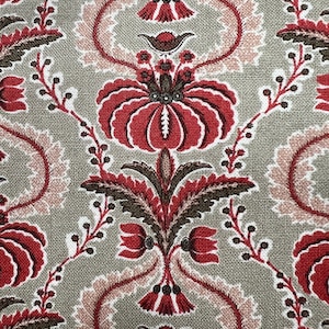 May include: Close-up of a fabric with a repeating floral pattern. The design features large red flowers with brown and white accents, set against a muted green background. The pattern includes stylized leaves and vines.