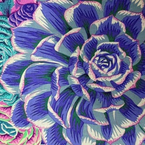 May include: Close-up of a vibrant floral pattern featuring a large, stylized succulent. The petals are a gradient of deep blue to light blue, with white and pink accents. Other flowers in shades of pink, green, and teal are also visible.