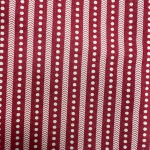 May include: Close-up of a fabric with a repeating pattern. The background is a deep red, with vertical stripes of white. The white stripes alternate between rows of small dots and rows of arrow-like shapes.