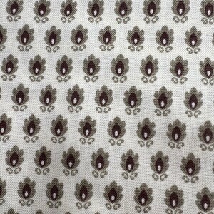 May include: Close-up of a fabric with a repeating floral pattern. The design features small, stylized flowers in shades of brown and gray, set against a cream-colored background. The fabric has a textured appearance, suggesting a woven material.