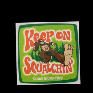 May include: Green and orange sticker with a cartoon Bigfoot walking and the text "Keep on Squatchin' Shawnee National Forest".