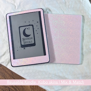 Puede incluir: Una funda rosa para lector de libros electrónicos y una funda a juego. La funda tiene un patrón floral holográfico alrededor de los bordes y una pantalla negra con el logotipo "Bookish Decals" con una luna creciente y estrellas. La funda tiene un patrón floral similar.