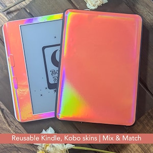 May include: Two iridescent orange Kindle or Kobo skins. One skin is on a device, displaying a graphic with a crescent moon and stars. The other skin is separate. The text "Reusable Kindle, Kobo skins | Mix & Match" is at the bottom.