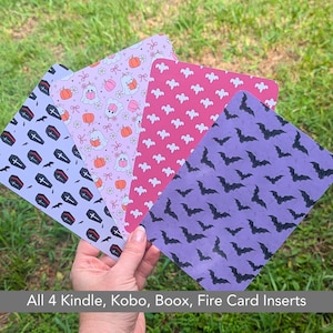 May include: Four Halloween-themed card inserts with different patterns. One insert has coffins and crosses on a lavender background. Another has ghosts, pumpkins, and bows on a pink background. The third has bats on a purple background. The fourth has ghosts on a pink background.