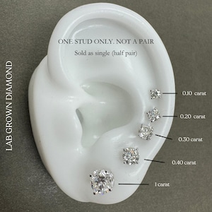 May include: A close-up of a white ear model with five lab-grown diamond studs of different sizes. The diamonds are labeled with their carat weight: 0.10 carat, 0.20 carat, 0.30 carat, 0.40 carat, and 1 carat. The text "ONE STUD ONLY. NOT A PAIR" and "Sold as single (half pair)" is also visible.