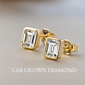 May include: A pair of gold earrings with square-shaped lab-grown diamonds.  LAB GROWN DIAMOND.
