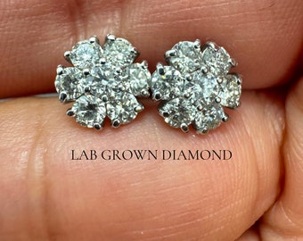 Puede incluir: Un par de pendientes de plata en forma de flor con pequeños diamantes de laboratorio transparentes. LAB GROWN DIAMOND está escrito debajo de los pendientes.