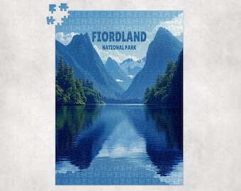 Könnte beinhalten: Ein fertiges Puzzle mit einer Landschaftsansicht des Fiordland Nationalparks. Das Bild zeigt einen See, der die umliegenden Berge und Bäume widerspiegelt, mit dem Text "FIORDLAND NATIONAL PARK" oben. Das Puzzle ist hauptsächlich blau.