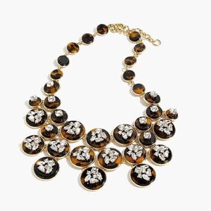 May include: A gold-toned necklace featuring a series of tortoiseshell-patterned, circular pendants. Each pendant is accented with a cluster of clear, sparkling crystals. The necklace has a delicate chain and clasp.