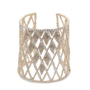 May include: A gold-toned cuff bracelet with a diamond-shaped lattice design. The bracelet is encrusted with numerous clear, sparkling rhinestones, creating a glamorous and eye-catching accessory. The open design allows for easy wear.