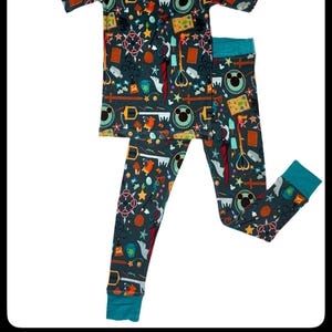 May include: A teal blue and green pajama set with a colorful print of Mickey Mouse and various Disney characters. The pajamas feature a short-sleeved top and long pants.