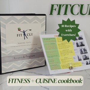May include: A black binder with a gray chevron pattern and the text "Fitness Cuisine" and "FIT CUI" on the cover. The binder is open to a page with the text "Work Out/Eat In!" and "Recipes & Program". A white sheet with the text "FITCUI" and "10 Recipes with Exercises!" is on a stand next to the binder.