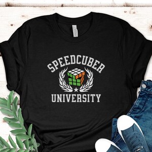 May include: Black t-shirt with a white graphic of a Rubik's Cube and the text "Speedcuber University".