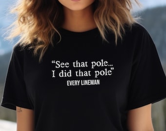 May include: Black t-shirt with white text that reads "See that pole... I did that pole" and "EVERY LINEMAN".