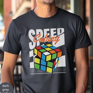 May include: Dark heather grey t-shirt with a vintage-style graphic of a Rubik's Cube and the text "Speed Cubing".