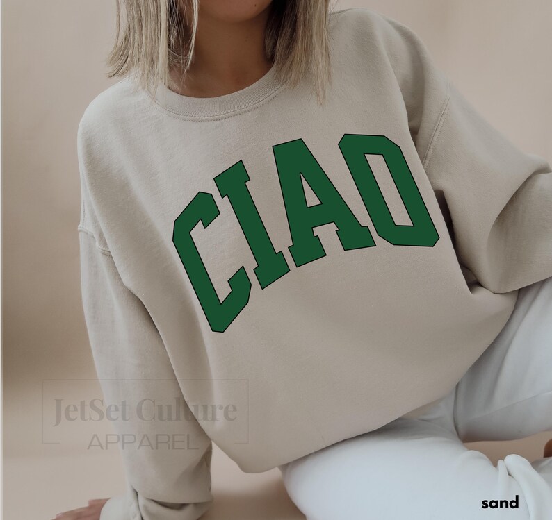 May include: A beige sweatshirt with the word "CIAO" printed in green letters in an arched style.