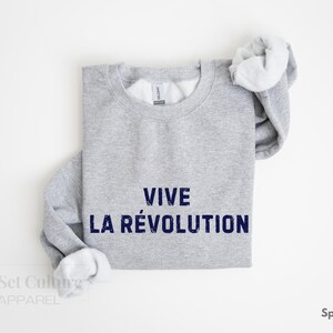 May include: A gray sweatshirt with the text "VIVE LA R&Eacute;VOLUTION" printed in blue.