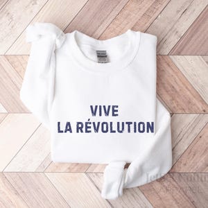 May include: White sweatshirt with the text "VIVE LA R&Eacute;VOLUTION" printed in blue.