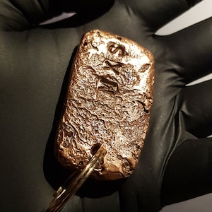 May include: A gold-colored metal keychain with a rectangular tag that says "1/2 oz" and "Silver".