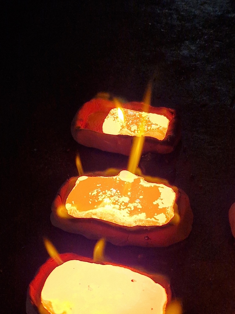 May include: Close-up of three glowing, rectangular objects with flames. The objects have a bright yellow-orange center and a red border, set against a dark background. The flames are yellow and orange.