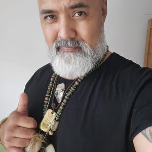Peut inclure: Un t-shirt noir avec un collier à plusieurs rangs orné de perles, d'un pendentif doré et d'un cristal transparent. Le collier comprend également une lanière en cuir, une garniture en fourrure et une grande défense blanche.
