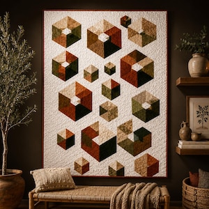 Op de afbeelding: Een rechthoekige quilt met een geometrisch patroon van zeshoeken in verschillende groottes in tinten roest, olijfgroen en beige. De zeshoeken zijn gerangschikt op een getextureerde witte achtergrond, wat een driedimensionaal kubeffect creëert.