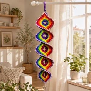 May include: A hanging spiral decoration made of crocheted yarn in a rainbow colour gradient, featuring five distinct sections. Each section has a silver star-shaped charm at its centre, and a larger silver star hangs from the bottom point.