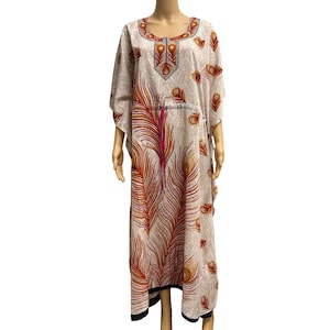May include: A cream-colored, floor-length kaftan dress with a peacock feather design. The dress features a scoop neckline and wide sleeves. The feather pattern includes shades of red, orange, and pink, with a black trim at the hem.