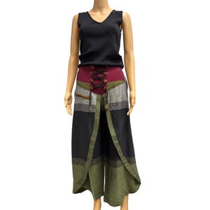 May include: A black sleeveless top paired with wide-leg pants. The pants feature a burgundy, olive green, gray, and black color block design with a lace-up front and a zipper pocket. The pants have a split front design.