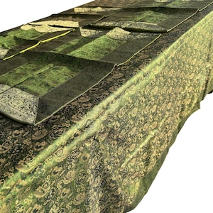 May include: A green and gold patterned tablecloth with matching placemats. The tablecloth and placemats have a floral design. The tablecloth is draped over a table. The placemats are folded and placed on top of the tablecloth.