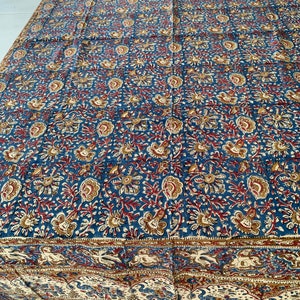 May include: A blue and red floral patterned fabric with a white border. The fabric has a traditional Indian design.
