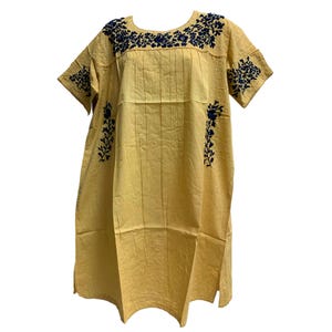 May include: A yellow, short-sleeved dress with navy blue floral embroidery. The dress features a round neckline and vertical pleats down the front. The embroidery is concentrated around the neckline, sleeves, and sides of the dress.