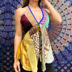 May include: A patchwork halter top in a variety of colors and patterns. The top features a deep V-neckline with a blue trim and a halter strap. The fabric is a mix of silk and other materials, creating a unique and bohemian look.