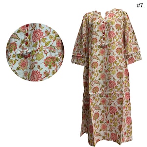 May include: A long, white floral print dress with a mandarin collar and three-quarter sleeves. The dress features a pattern of pink and green flowers and foliage. The dress has red buttons down the front and is labeled with the number 7.