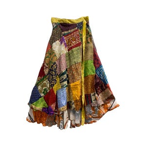 Op de afbeelding: Een kleurrijke patchwork wikkelrok met een gele band. De rok is gemaakt van verschillende stoffen en patronen, waaronder bloemen, paisley en geometrische ontwerpen.