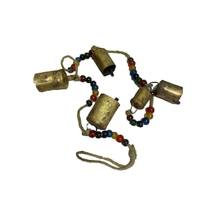 May include: A string of gold bells with colorful beads, hanging from a natural twine cord. The bells are attached to the cord with small metal rings.