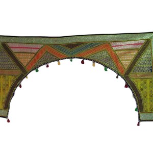 Op de afbeelding: Een decoratieve textielen valance met een geometrisch ontwerp. De valance heeft een verscheidenheid aan kleuren, waaronder groen, oranje, geel en bruin. Het heeft een gebogen onderrand met kleine kwastjes en een zwarte rand.