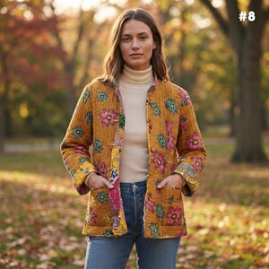 May include: A mustard yellow quilted jacket featuring a vibrant floral pattern in shades of pink, teal, and white. The jacket has long sleeves, a straight hem, two front patch pockets, and a button-front closure, worn over a cream turtleneck.
