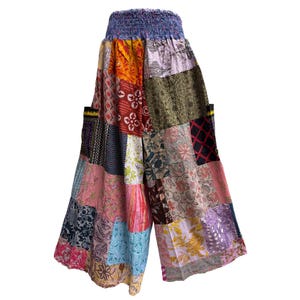 May include: Patchwork palazzo pants with a blue elastic waistband. The wide-leg pants feature a variety of colorful fabric patches in floral and geometric patterns. The pants are made of a lightweight material.