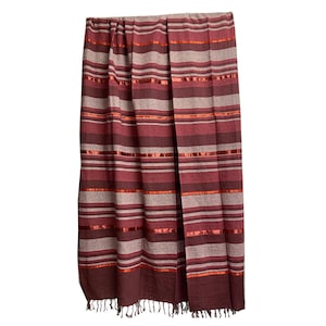 May include: A burgundy and gray striped throw blanket with orange ribbon accents. The blanket has a fringed edge and is made of a soft, woven material. The stripes run horizontally across the blanket.