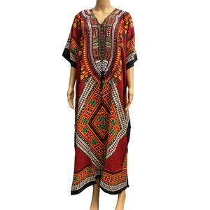 May include: A red, patterned dashiki dress with a V-neck and short sleeves. The dress features a geometric design in green, yellow, and white, with black trim on the sleeves and hem. A black drawstring is at the waist.